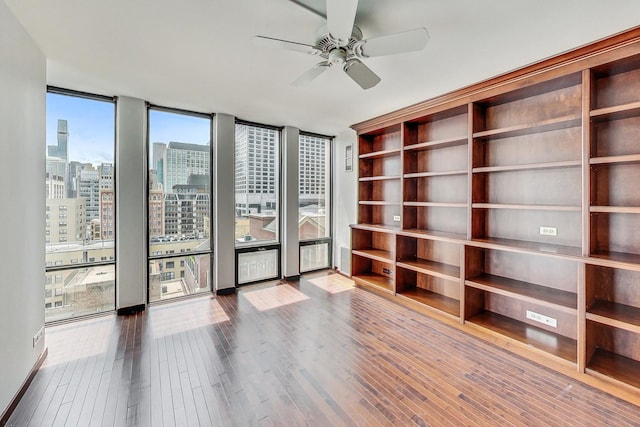 empty room with hardwood / wood-style flooring, expansive windows, and ceiling fan