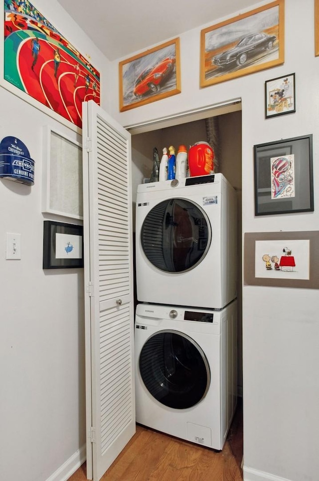 laundry room featuring stacked washing maching and dryer and wood-type flooring