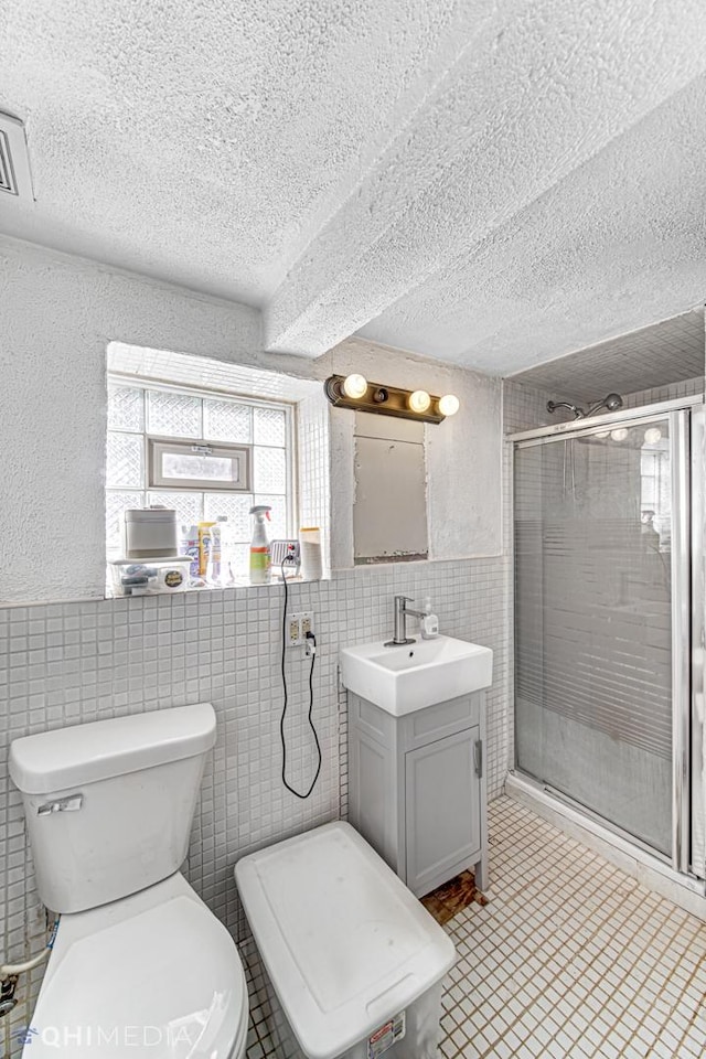 bathroom featuring a shower with shower door, a textured ceiling, and tile walls