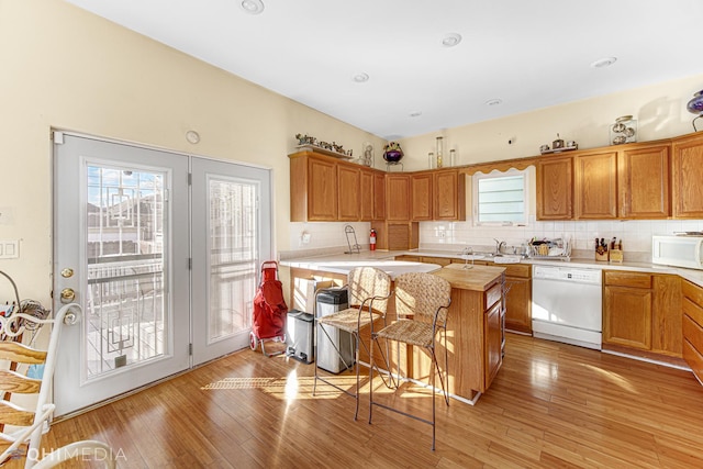 kitchen featuring light hardwood / wood-style floors, white appliances, sink, and tasteful backsplash