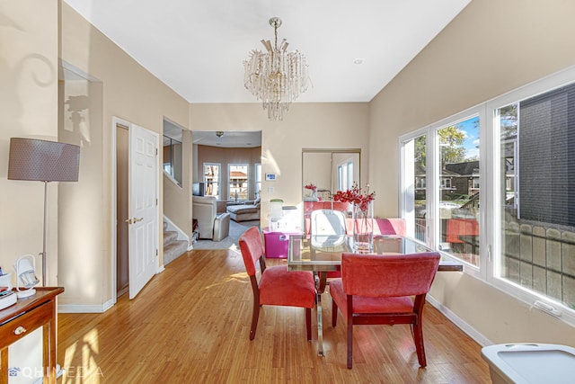 dining space with light hardwood / wood-style floors and a notable chandelier