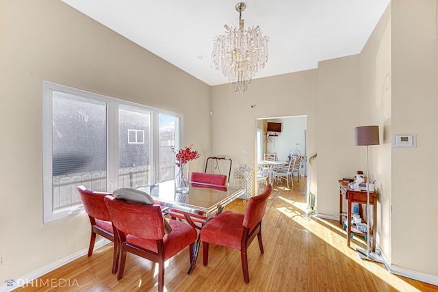 dining room featuring an inviting chandelier, lofted ceiling, and light wood-type flooring