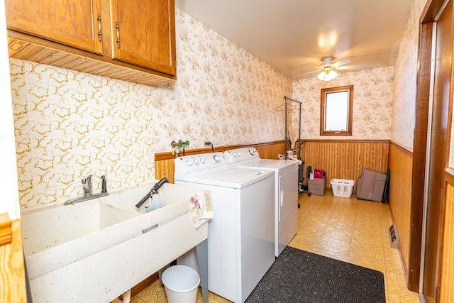 laundry area with washer and clothes dryer, wood walls, cabinets, sink, and ceiling fan