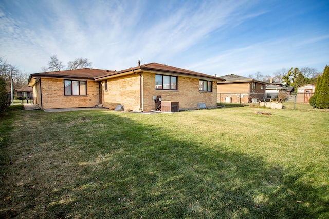 rear view of house featuring central AC unit and a lawn