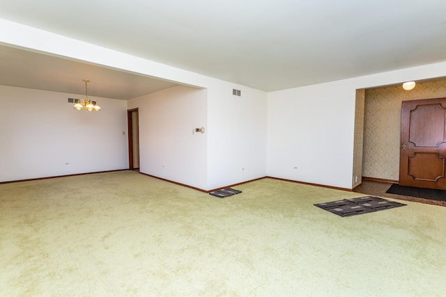 carpeted spare room with an inviting chandelier