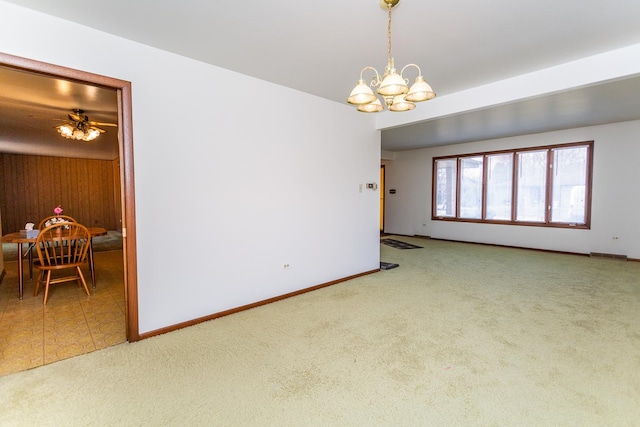 carpeted empty room featuring ceiling fan with notable chandelier