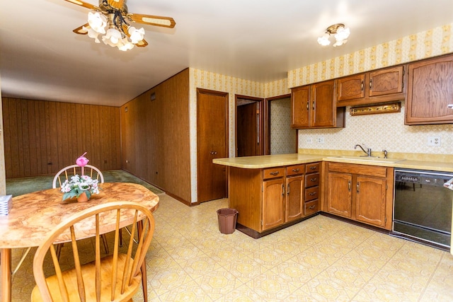 kitchen featuring kitchen peninsula, ceiling fan, sink, dishwasher, and wood walls