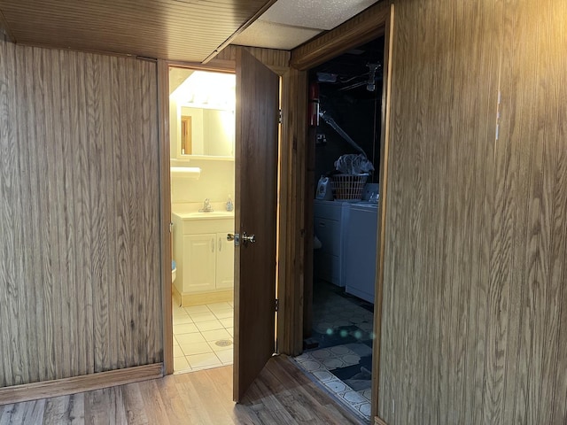 corridor featuring sink, washer and clothes dryer, and light hardwood / wood-style flooring