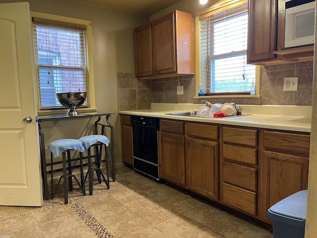 kitchen with tasteful backsplash, sink, and black dishwasher