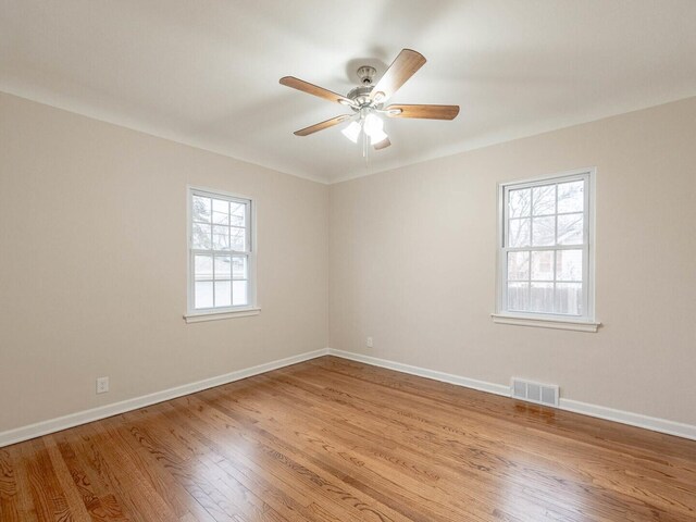 spare room with light wood-type flooring, a wealth of natural light, and ceiling fan