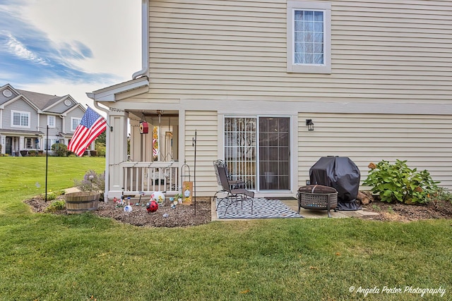 back of house with a yard and an outdoor fire pit