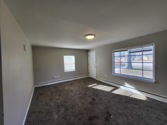 carpeted empty room featuring plenty of natural light and a baseboard heating unit