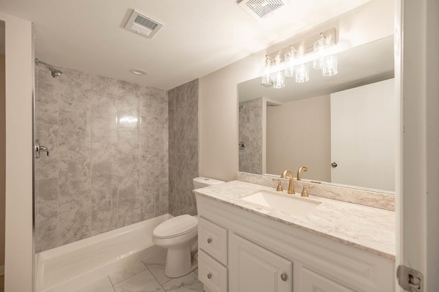 bathroom with tiled shower, vanity, and toilet