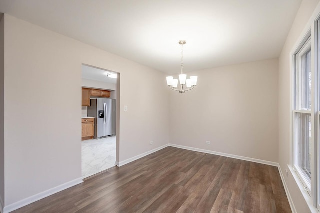 spare room with dark hardwood / wood-style floors and an inviting chandelier