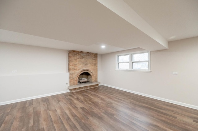 unfurnished living room featuring dark hardwood / wood-style floors and a brick fireplace