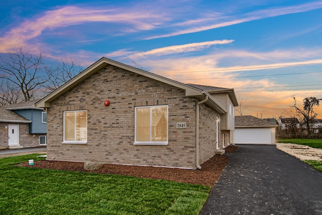 property exterior at dusk featuring a garage, a yard, and an outbuilding