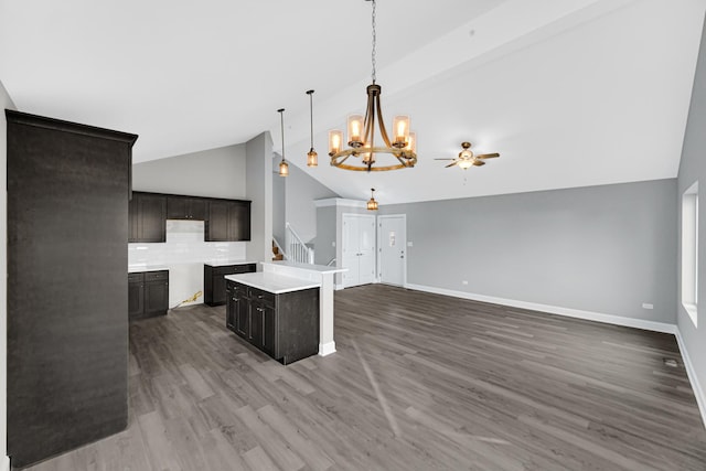 kitchen with pendant lighting, vaulted ceiling, backsplash, hardwood / wood-style flooring, and a kitchen island