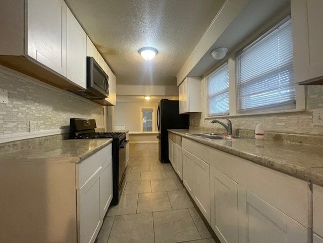 kitchen with light stone countertops, tasteful backsplash, white cabinetry, and black appliances