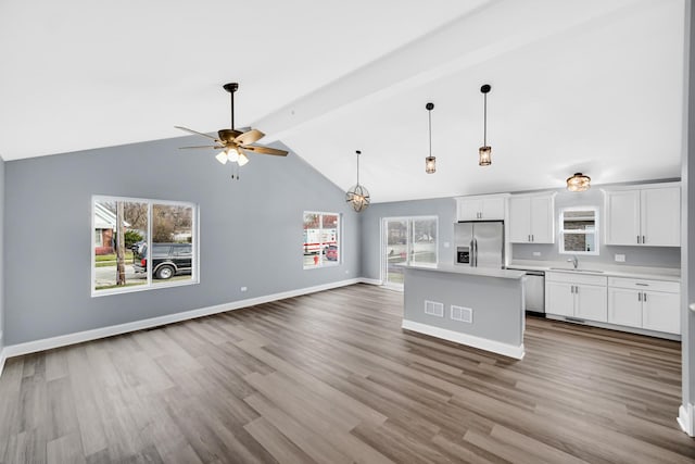 kitchen with white cabinetry, sink, stainless steel appliances, plenty of natural light, and a kitchen island