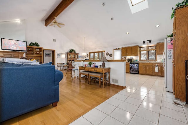 living room featuring beam ceiling, a skylight, ceiling fan, high vaulted ceiling, and light hardwood / wood-style floors