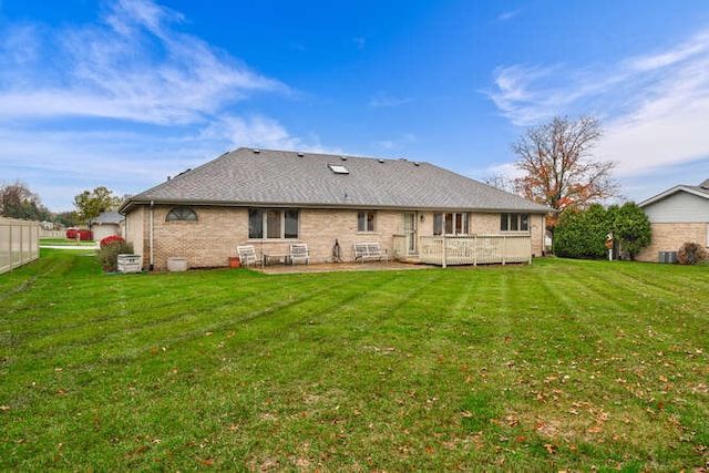 rear view of house with a lawn, a wooden deck, and a patio