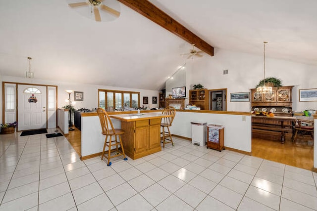 kitchen with kitchen peninsula, pendant lighting, light tile patterned floors, and high vaulted ceiling