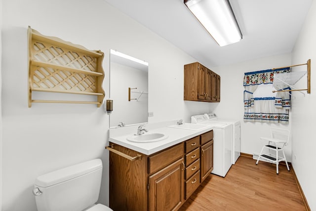 bathroom with hardwood / wood-style floors, toilet, washing machine and dryer, and vanity