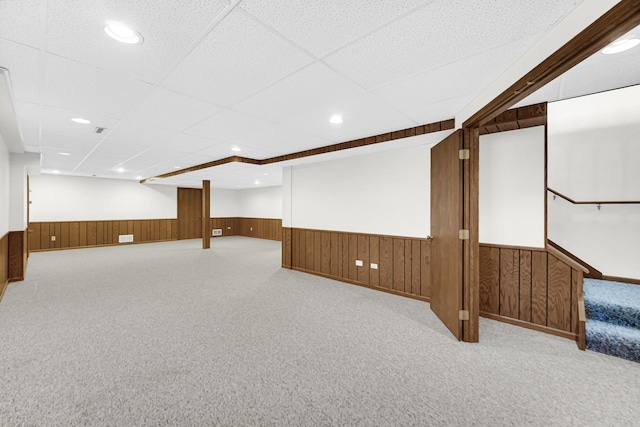 basement with a paneled ceiling and light carpet