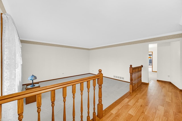 hall with crown molding and light hardwood / wood-style flooring