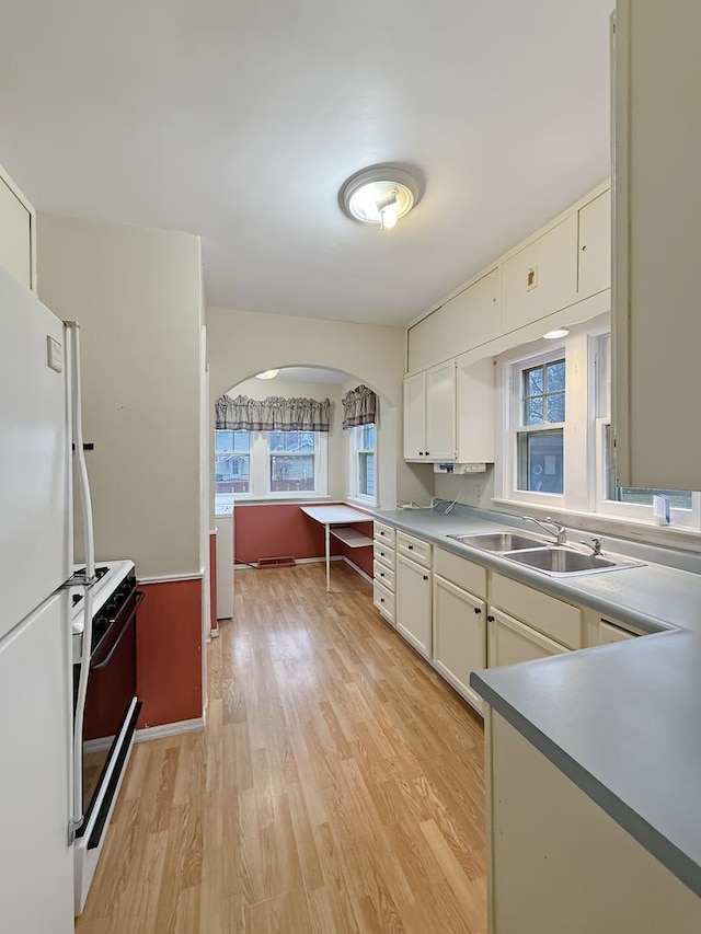 kitchen with a healthy amount of sunlight, white appliances, light hardwood / wood-style floors, and sink