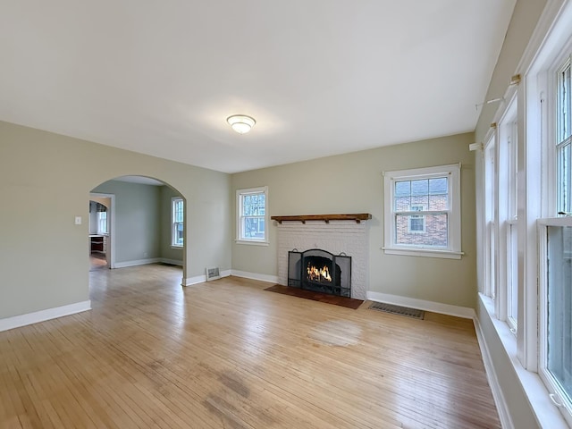 unfurnished living room with a brick fireplace and light hardwood / wood-style flooring