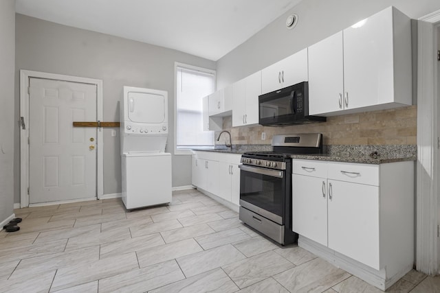 kitchen with gas stove, white cabinetry, stacked washing maching and dryer, dark stone countertops, and decorative backsplash