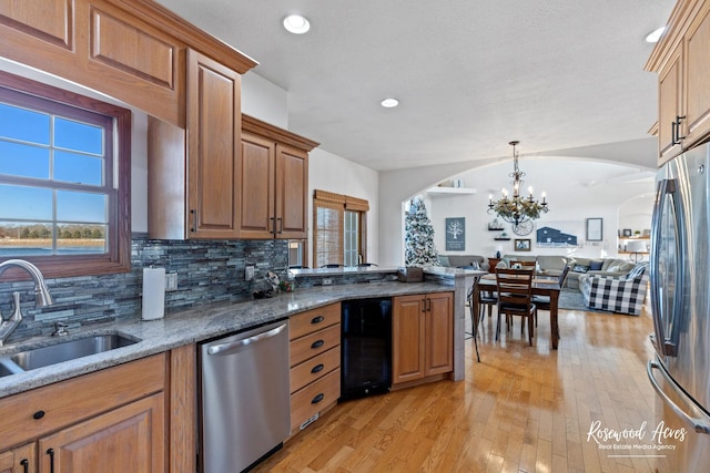 kitchen with pendant lighting, lofted ceiling, backsplash, light wood-type flooring, and appliances with stainless steel finishes