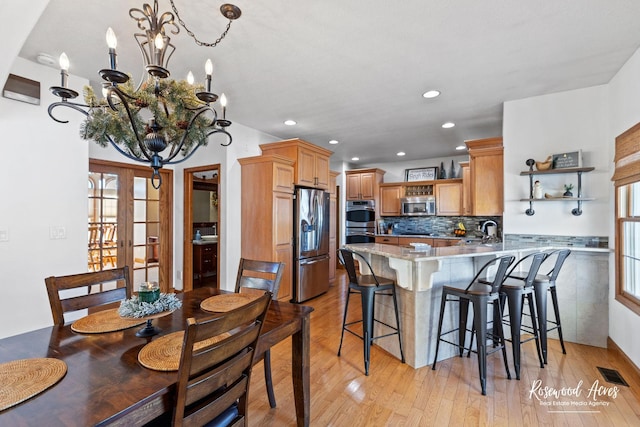 kitchen featuring a breakfast bar area, kitchen peninsula, light wood-type flooring, and appliances with stainless steel finishes