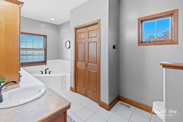 bathroom featuring tiled tub, tile patterned flooring, and vanity