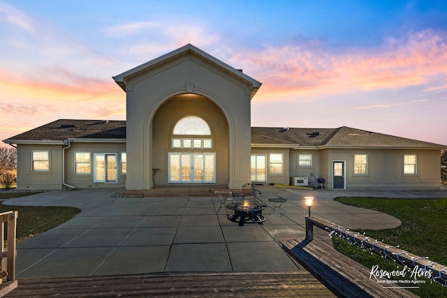 back house at dusk with a patio area and an outdoor fire pit