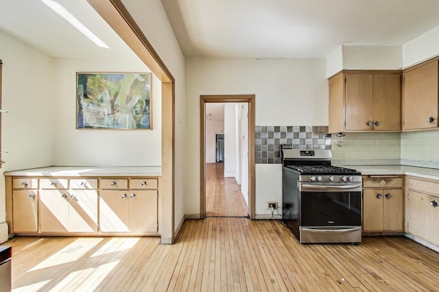 kitchen featuring decorative backsplash, light hardwood / wood-style flooring, and stainless steel gas range oven