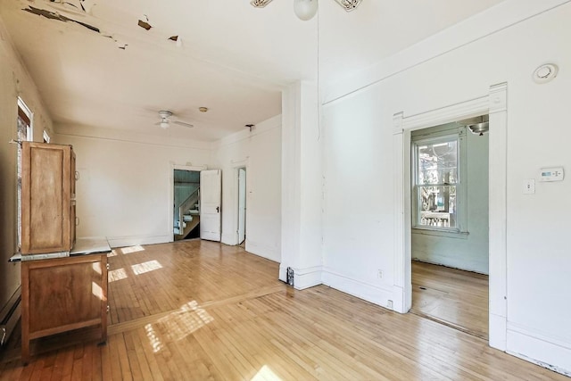 unfurnished room featuring light wood-type flooring, ceiling fan, a baseboard radiator, and a healthy amount of sunlight