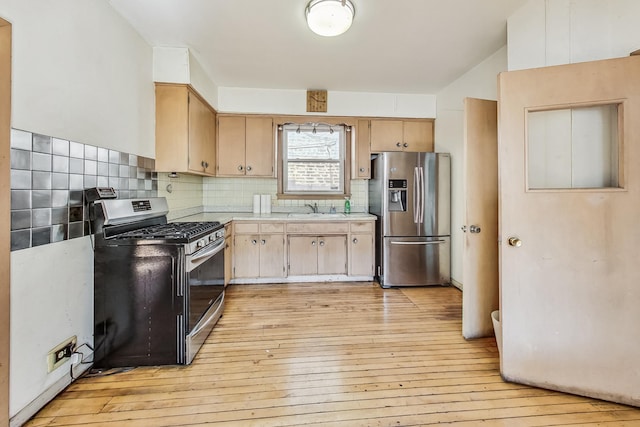 kitchen featuring stainless steel appliances, sink, tasteful backsplash, and light wood-type flooring