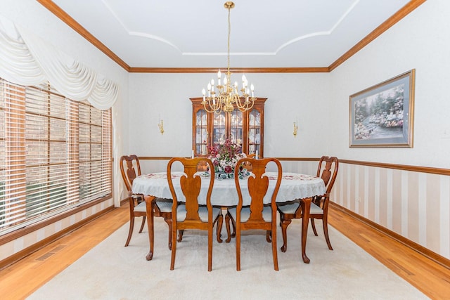 dining space featuring a chandelier, light hardwood / wood-style floors, and ornamental molding