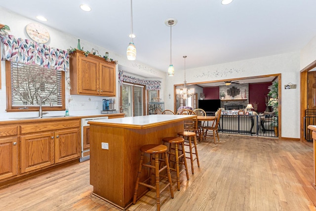 kitchen featuring a kitchen breakfast bar, sink, dishwasher, light hardwood / wood-style floors, and a kitchen island