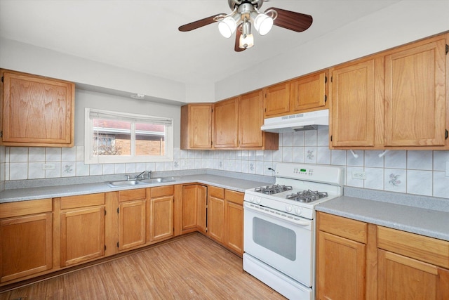 kitchen featuring light wood-type flooring, backsplash, white gas range, ceiling fan, and sink