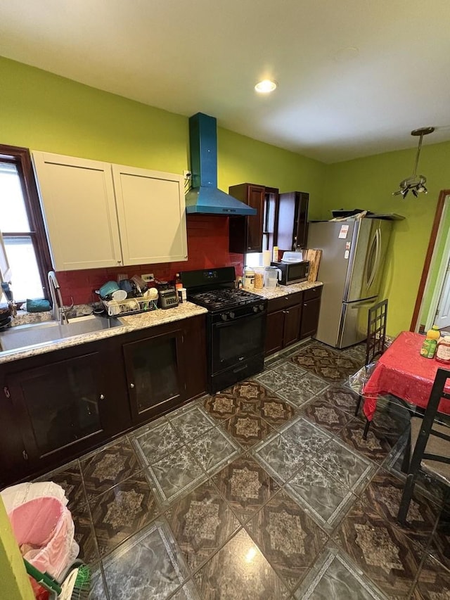 kitchen featuring dark brown cabinetry, wall chimney range hood, sink, and appliances with stainless steel finishes