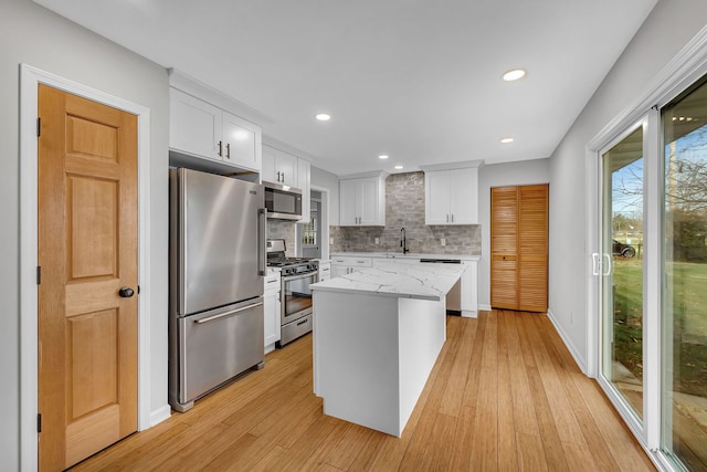 kitchen with a center island, white cabinets, sink, light hardwood / wood-style flooring, and stainless steel appliances