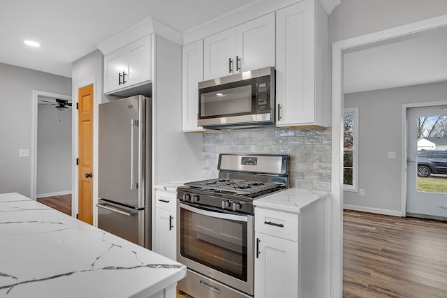 kitchen featuring light stone countertops, backsplash, stainless steel appliances, dark wood-type flooring, and white cabinets