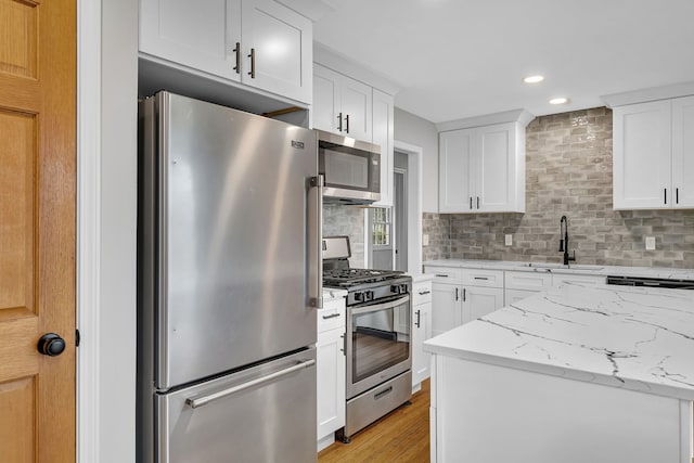 kitchen featuring light stone counters, stainless steel appliances, sink, light hardwood / wood-style floors, and white cabinetry