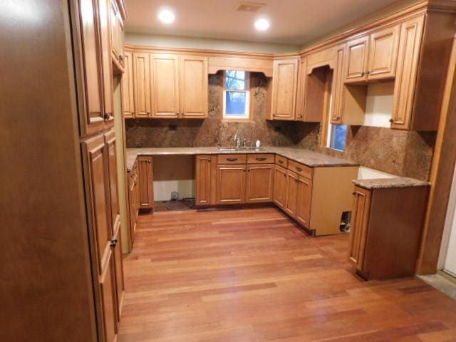 kitchen featuring decorative backsplash, light brown cabinets, light wood-type flooring, and sink