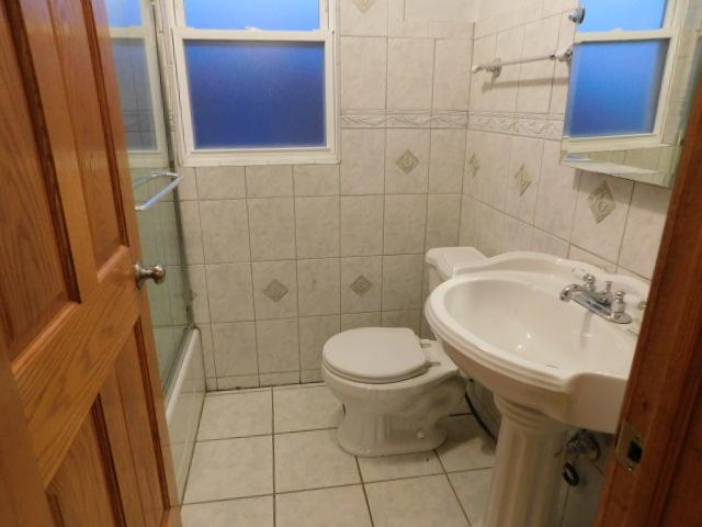 bathroom featuring tile patterned flooring, bath / shower combo with glass door, tile walls, and toilet