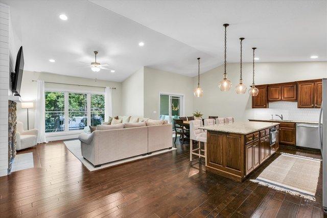 kitchen with a breakfast bar, a center island, dark wood-type flooring, and vaulted ceiling