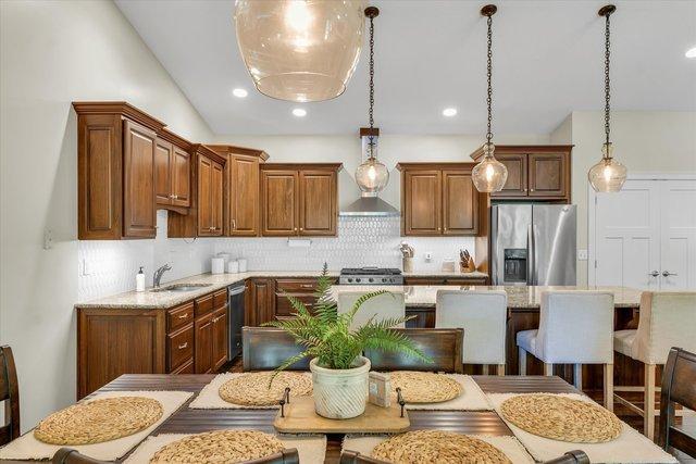 kitchen with stainless steel refrigerator with ice dispenser, backsplash, sink, pendant lighting, and a kitchen island